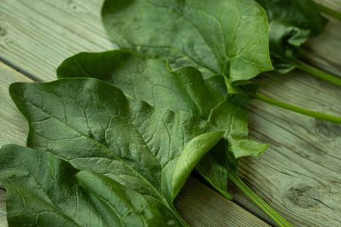 Parlak yeşil ıspanak yaprağının görülebilir dokusu ve küçük su damlacıkları kırsal ahşap bir yüzeye yerleştirilmiş yakın çekim görüntüsü. Sağlık ve yemek için mükemmel..