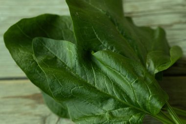 Parlak yeşil ıspanak yaprağının görülebilir dokusu ve küçük su damlacıkları kırsal ahşap bir yüzeye yerleştirilmiş yakın çekim görüntüsü. Sağlık ve yemek için mükemmel..