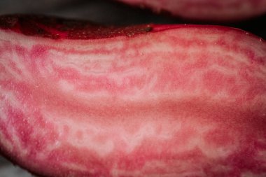 Kırsal ahşap bir zemine yerleştirilmiş, parlak pembe ve kırmızı bilyeli iki kırmızı patatesin kesiti..