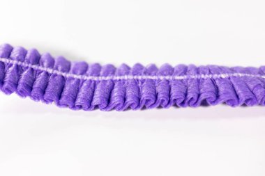 Mor, buruşuk, tek kullanımlık, görünür dikişleri ve dokusu olan temiz, beyaz bir arka plana yerleştirilmiş bir saç bandının detaylı bir görüntüsü..