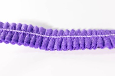 Mor, buruşuk, tek kullanımlık, görünür dikişleri ve dokusu olan temiz, beyaz bir arka plana yerleştirilmiş bir saç bandının detaylı bir görüntüsü..