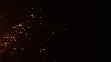 Ateşten kıvılcımlar ve kömürler saçıyor. Siyah arka planda yanan turuncu ateş ve duman parçacıkları, ateş yanıp sönüyor.