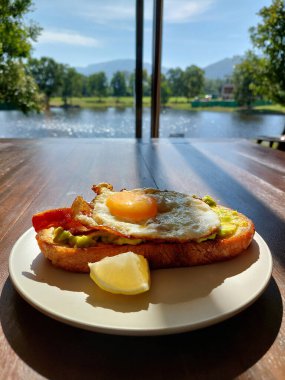 Khao Yai manzaralı bir tabak yumurta, pastırma ve avokado tostu..