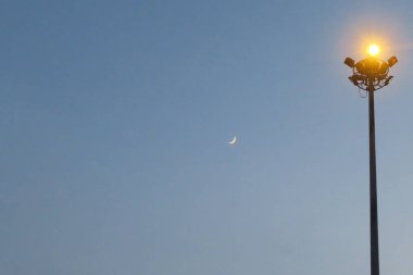 Street lamp post and little moon in grey sky, Bangkok, Thailand.