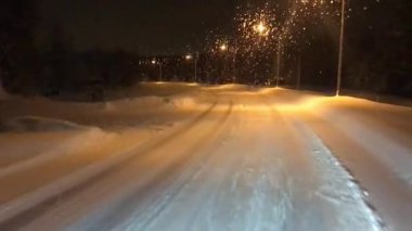Finlandiya 'nın Rovaniemi kentinde, otobüsün ön camından karlı bir yolun gece manzarası uzanıyor..