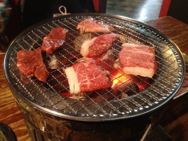 Japon restoranında kömür ocağında ızgara yapılmış çiğ et dilimleri..