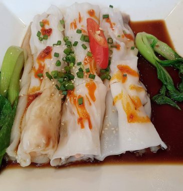 Çin restoranında beyaz bir tabakta servis edilen haşlanmış pirinç erişteli börekler.