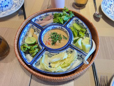 Hindistancevizi sütüyle karıştırılmış acı biber ezmesi, haşlanmış sebzelerle servis edilmiş.