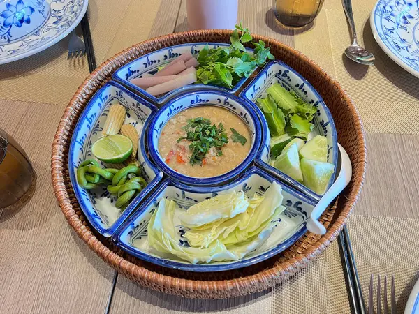 Hindistancevizi sütüyle karıştırılmış acı biber ezmesi, haşlanmış sebzelerle servis edilmiş.