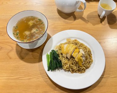 Dilimlenmiş haşlanmış tavukla kurutulmuş erişte ve yanında da Wonton çorbası. 