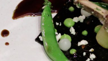 Himalaya sarımsağından yapılmış siyah dikdörtgen bir tabanda servis edilen kemikli kuzu eti. 