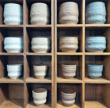 Ahşap bir rafta sergilenen el yapımı porselen seramik çay fincanları