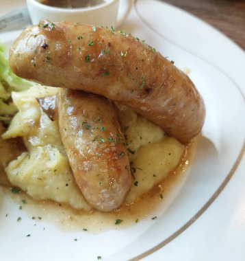 Soslu sosis ve patates püresi ve yanında salata.