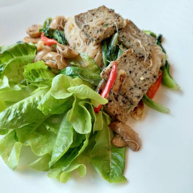 Tofu ve mantarlı ev yapımı kızarmış pirinç eriştesi.