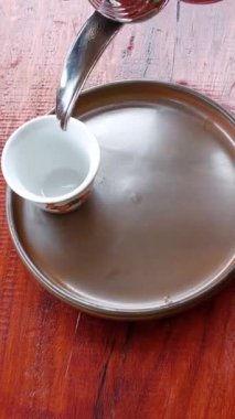 Çaydanlıktan küçük bir fincana bitkisel kahve dökülüyor.