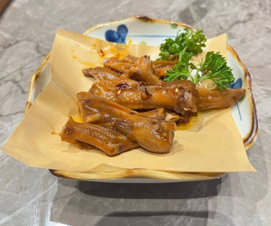 Kırmızı et suyunda pişirilmiş ördek bacağı, yemek kalitesinde kağıt peçeteyle servis edilir.