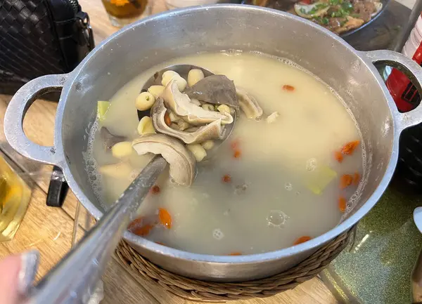 Biberli domuz çorbası ve Çin bitkisi, metal bir tencerede servis edilir..