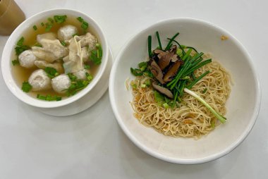 Üzeri soğan ve şitake mantarıyla kaplı kuru erişteler, domuz köftesi ve domuz pastırması dolu berrak çorba ile servis ediliyor..