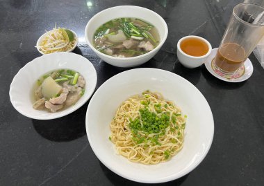 Üzeri soğanlı kuru erişte, iki kase domuz kemiği çorbası ile servis edilir.