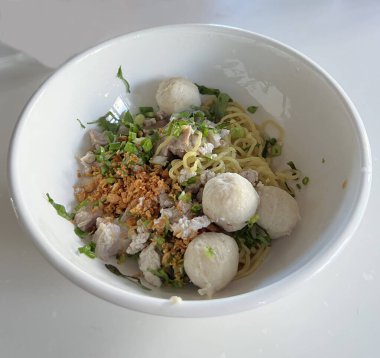 Kızarmış sarımsak ve kişniş soslu domuz köfteli kuru erişte..