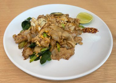 Kızarmış geniş pirinç eriştesi, siyah soya sosu, domuz eti, yumurta ve Çin brokolisi..