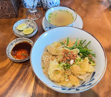 Kızarmış sarımsaklı, yanında çorba ve limonla servis edilen kurutulmuş erişte..