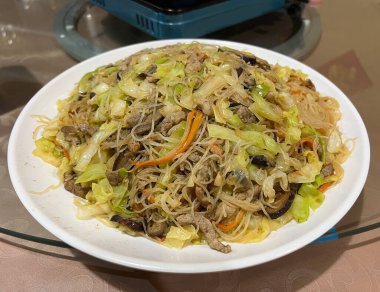 Büyük tabak Hong Kong usulü kızarmış erişte, yanında domuz eti, lahana ve havuç..