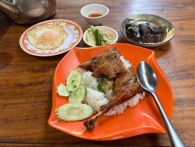 Üzerine ızgara tavuk budu, kızarmış yumurta, haşlanmış tavuk kanı, salamura sebze ve sosla servis edilen pilav..