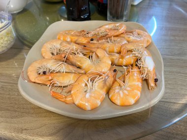 Çin yemek masasında dönen cam tabakla servis edilen buğulanmış karides.