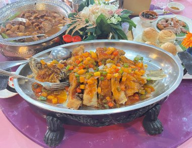 Çin tatlısı ve ekşi sosuyla karıştırılmış levrek, metal bir tabakta servis edilir..