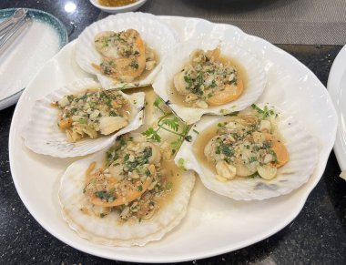 Sarımsaklı tereyağlı deniz tarağı, bir deniz ürünleri restoranında masada servis edilir.