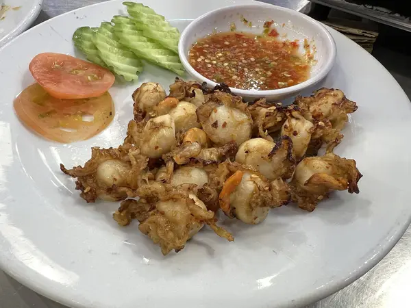 Kızarmış deniz tarağı, sarımsak ve acı biber, deniz ürünleri sosuyla servis edilir..