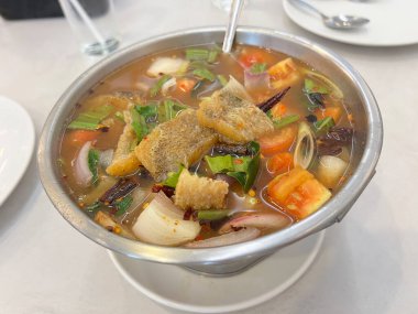 Kızarmış yılan başı balıklı, domatesli, soğanlı ve kişniş soslu baharatlı çorba.