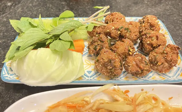 Kızarmış domuz eti, taze sebzelerle servis edilir.