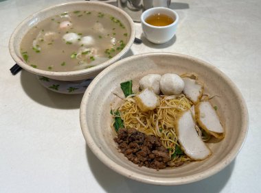 Geleneksel mee pok noodle stili, domuz eti, köfte ve wonton çorbası ile servis edilir.