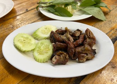 Dilimlenmiş salatalıkla servis edilen Tayland usulü ızgara domuz bağırsağı.