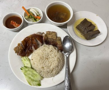 Kızarmış ördek ve kızarmış domuz pirinci, çorba, sebze turşusu, tavuk kanı ve baharatlı sos ile servis edilir.