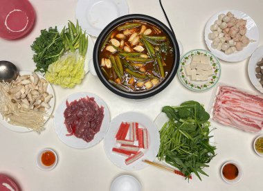 Sıcak tencere yemeği için çorba ve malzemelerle dolu elektrikli bir tencere.