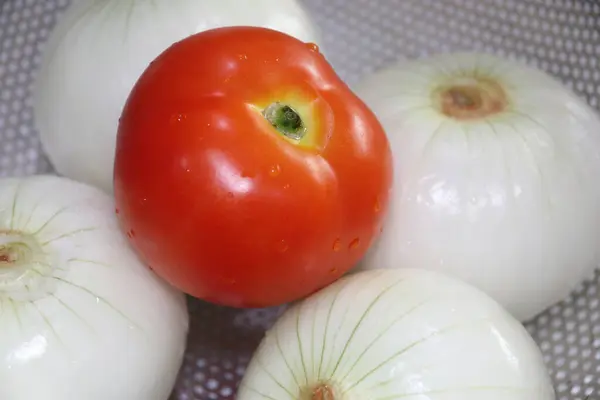 Paslanmaz çelik kevaşede soyulmuş soğan ve taze domates.