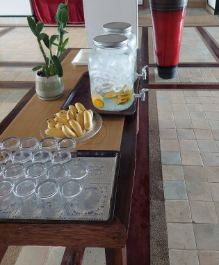 İçme bardakları, meyveler ve soğutulmuş suyla doldurulmuş cam haznelerin yer aldığı düzenli bir düzen.