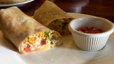 Luang Prabangstyle burrito yumurtalar, jambon, çedar ve taze sebzelerle dolu, salsa ile servis edilir.