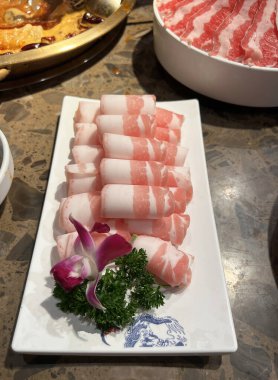 Bir Mala restoranının yemek masasında bir tabak dilimlenmiş domuz eti.