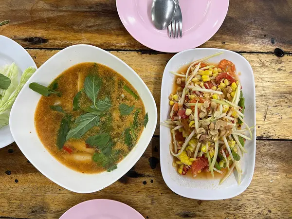 Mısır ve baharatlı domuz çorbası ile servis edilen Tayland usulü papaya salatası.