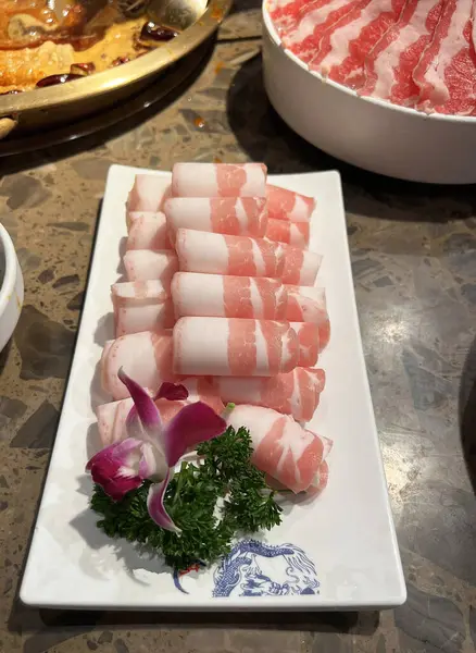 Bir Mala restoranının yemek masasında bir tabak dilimlenmiş domuz eti.