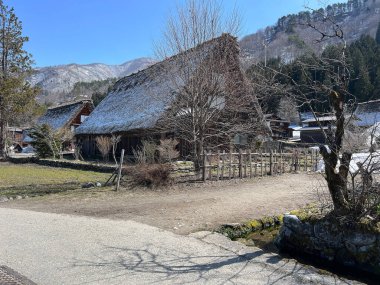 Geleneksel evler ve tarihi binalar Shirakawa-go Köyü 'nde sıradağlarla çevrili.