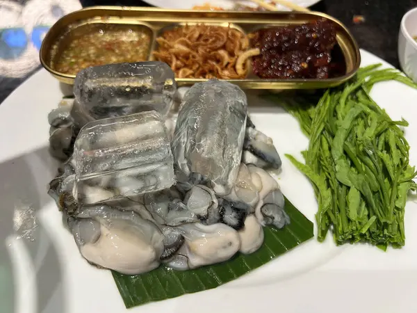 Baharatlı biber ezmesi, kızarmış soğan, limon ve bitkilerle servis edilen Tayland usulü taze istiridye.