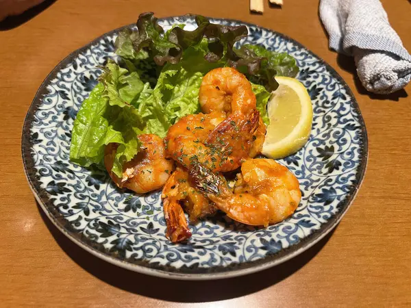 Japon usulü soslu kızarmış karides, marul ve limon dilimleriyle servis edilir.