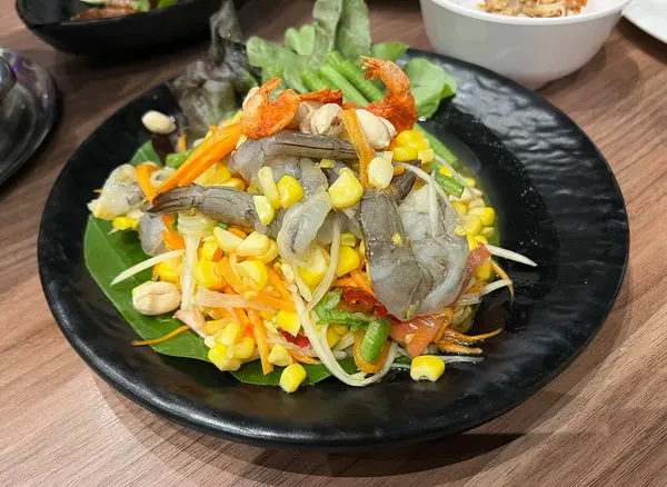 Tatlı mısırla karıştırılmış baharatlı Tayland papayası salatası ve taze karides.