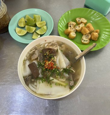 Çin hamur tatlısı ve limon dilimleriyle servis edilen domuz etli erişte çorbası.