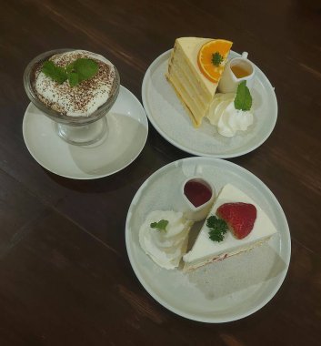 Çilekli pasta, portakallı pasta ve yemek masasında servis edilen tiramisu.